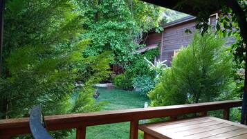 A wooden deck with a view of a lush garden and a wooden building in the background.