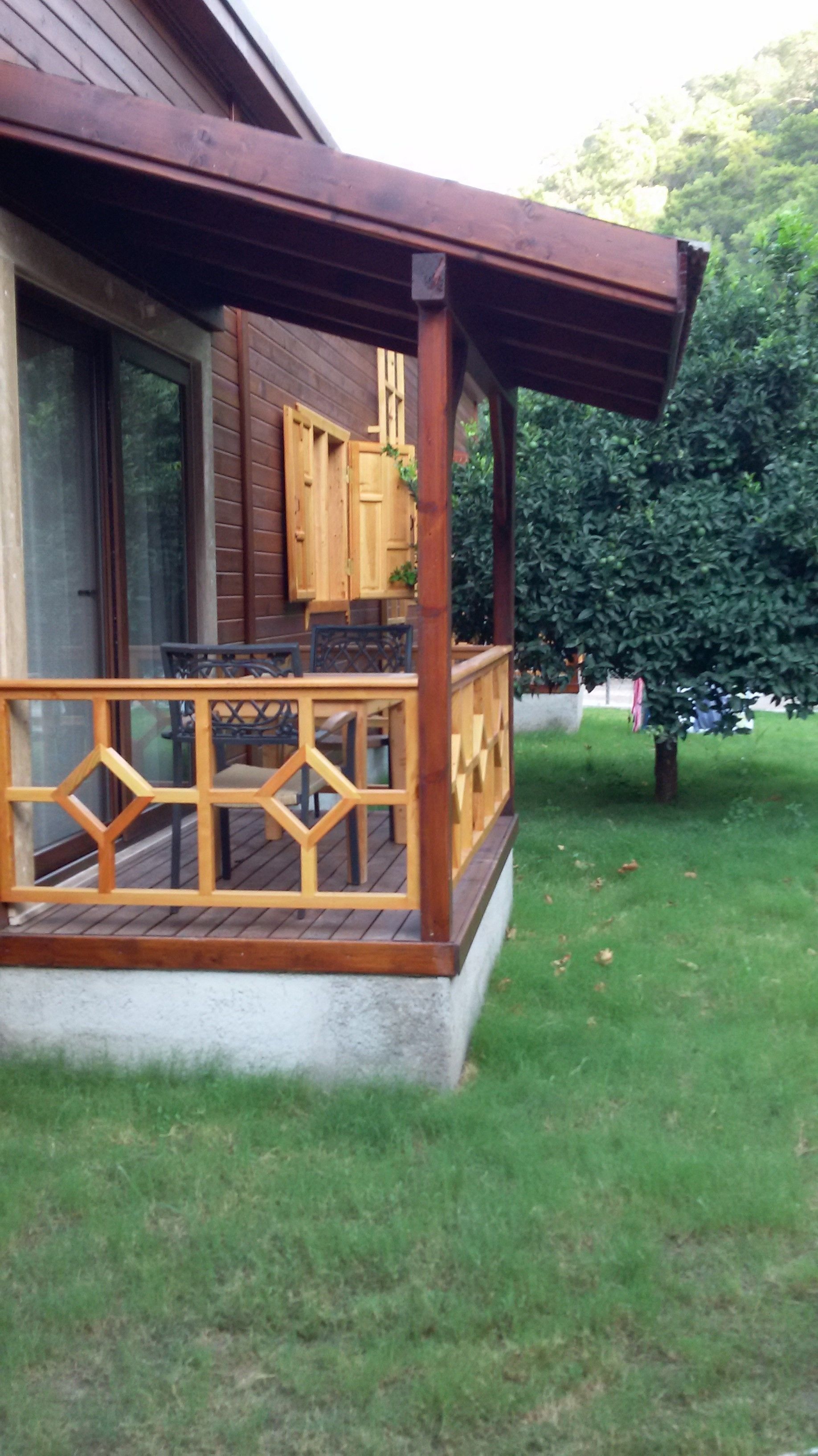 A wooden deck with a railing, a window, and a door.