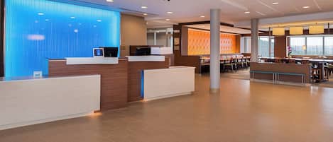 Eine geräumige Hotelhalle mit Rezeption, Sitzgelegenheiten und großen Fenstern.