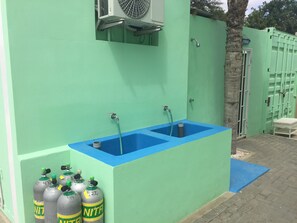 Un mur vert avec un évier bleu et trois bouteilles de NITRO.