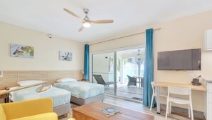 Hotelkamer met twee bedden, een bureau, een stoel, een televisie en een balkon met uitzicht.