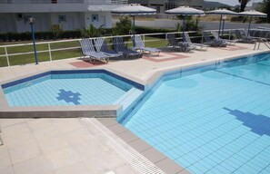 Una piscina al aire libre, sombrillas, sillones reclinables de piscina