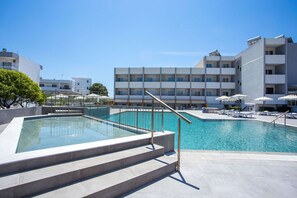 Una piscina al aire libre, sombrillas, tumbonas