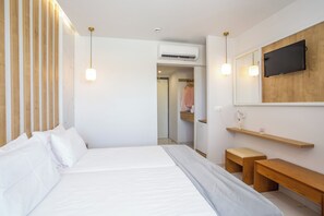 A modern bedroom with a large bed, bedside tables, a wardrobe, and a TV mounted on the wall. - Tsampika Hotel (Rhodes)