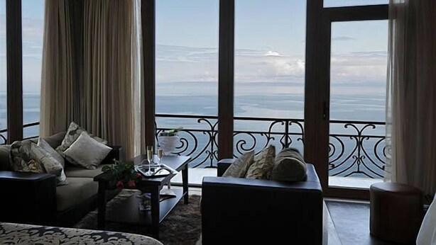 A room with a large window offering a view of the sea. There are two sofas and a coffee table with a plant. - Riviera Hotel  (Baku)