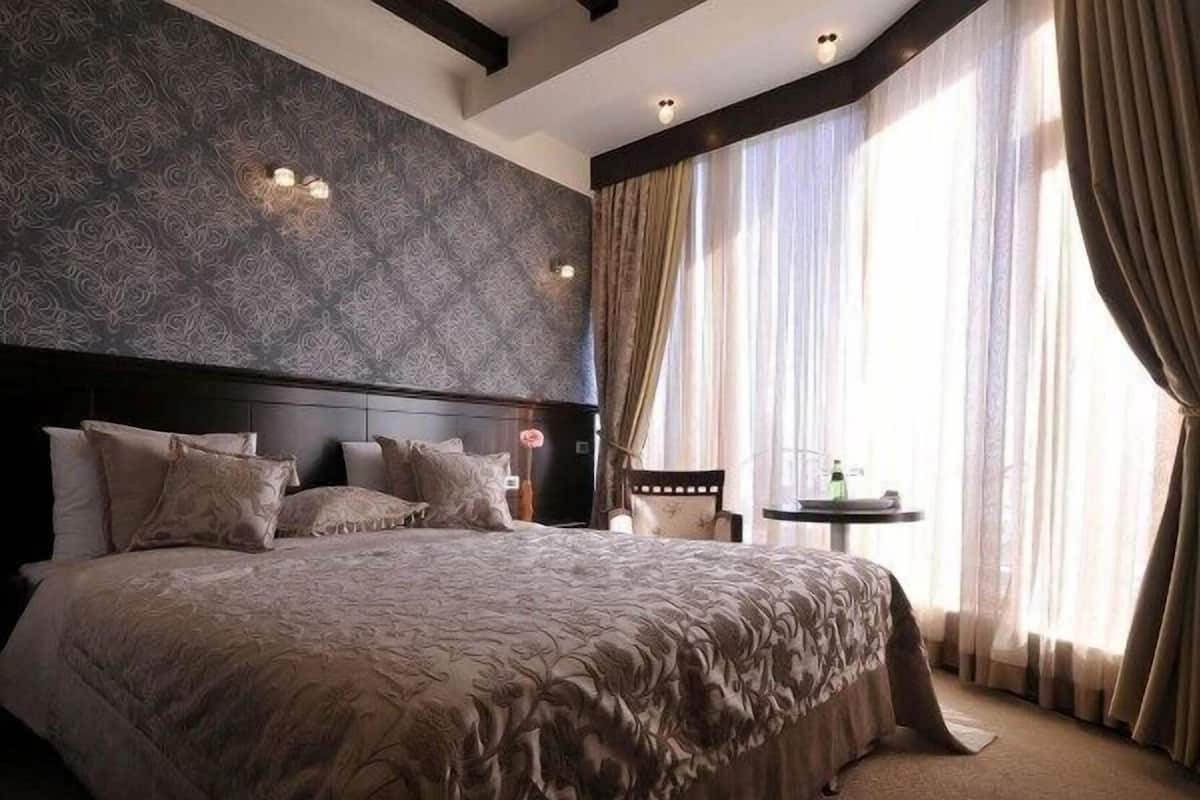 Una camera da letto con un letto grande, un comodino, una sedia e un tavolo con una bottiglia.