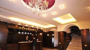 A reception area with a reception desk, a chandelier, and a staircase. - Riviera Hotel  (Baku)