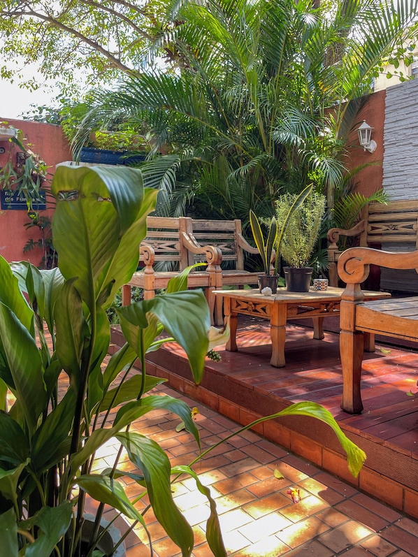 Un patio al aire libre con mobiliario de madera y plantas en macetas.