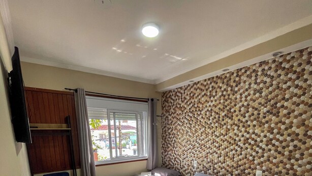 A hotel room with two beds, a desk, a TV, and a window with curtains. - Pousada dos Franceses (São Paulo)
