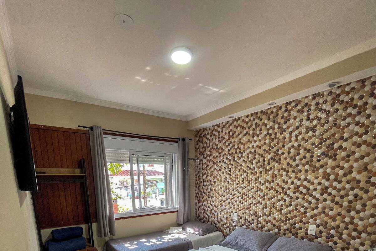 A hotel room with two beds, a desk, a TV, and a window with curtains.