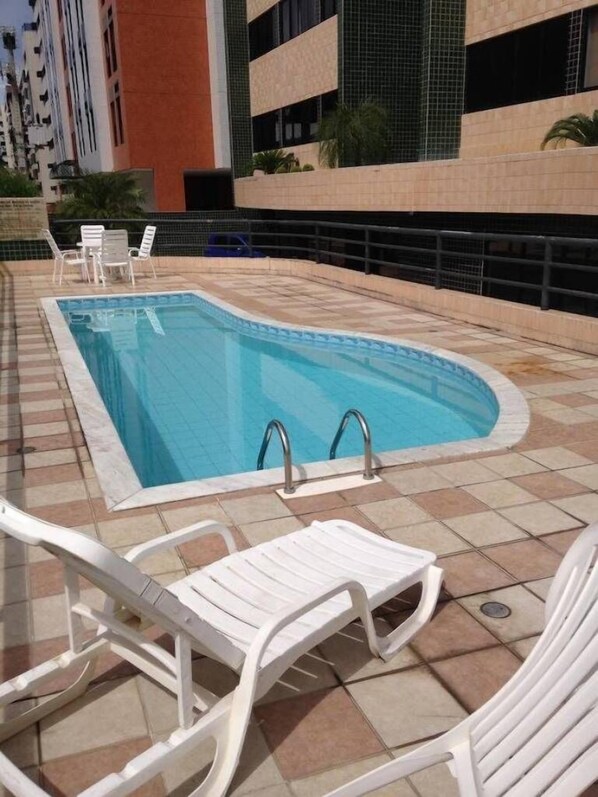 Una piscina al aire libre, sillones reclinables de piscina