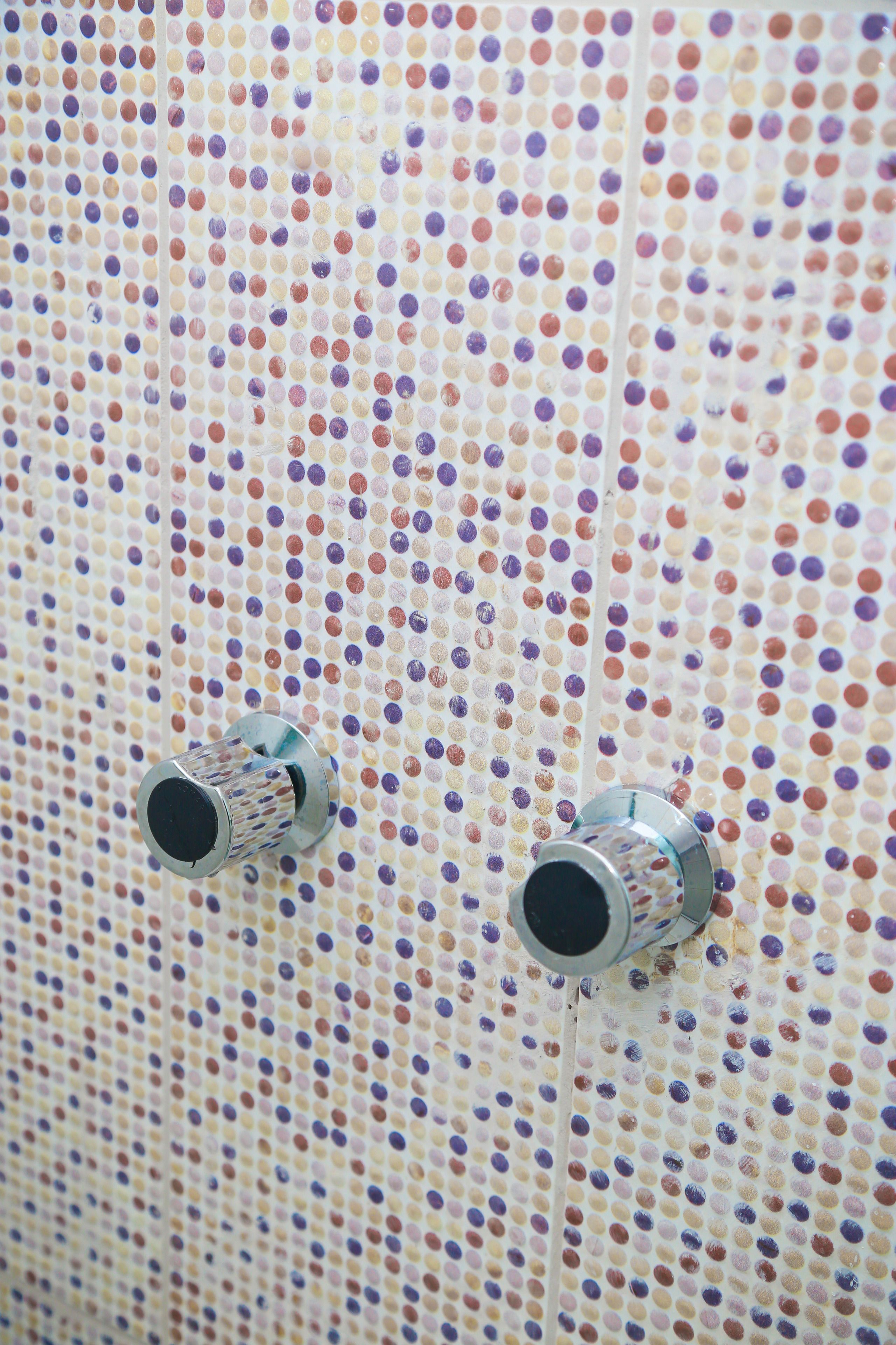 Una pared con estampado de lunares y dos elementos metálicos.