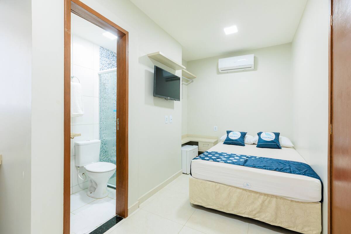 Une chambre à coucher comprenant un lit, une télévision, un climatiseur et une petite table de chevet.