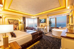 Een luxe hotelkamer met een groot bed, een zithoek, een badkuip en een televisie.
