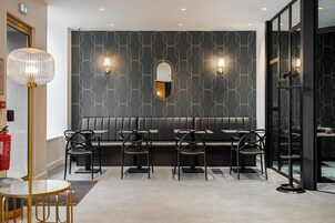 Um interior moderno com parede estampada em preto, uma mesa redonda e quatro cadeiras em frente a um banco de couro preto.