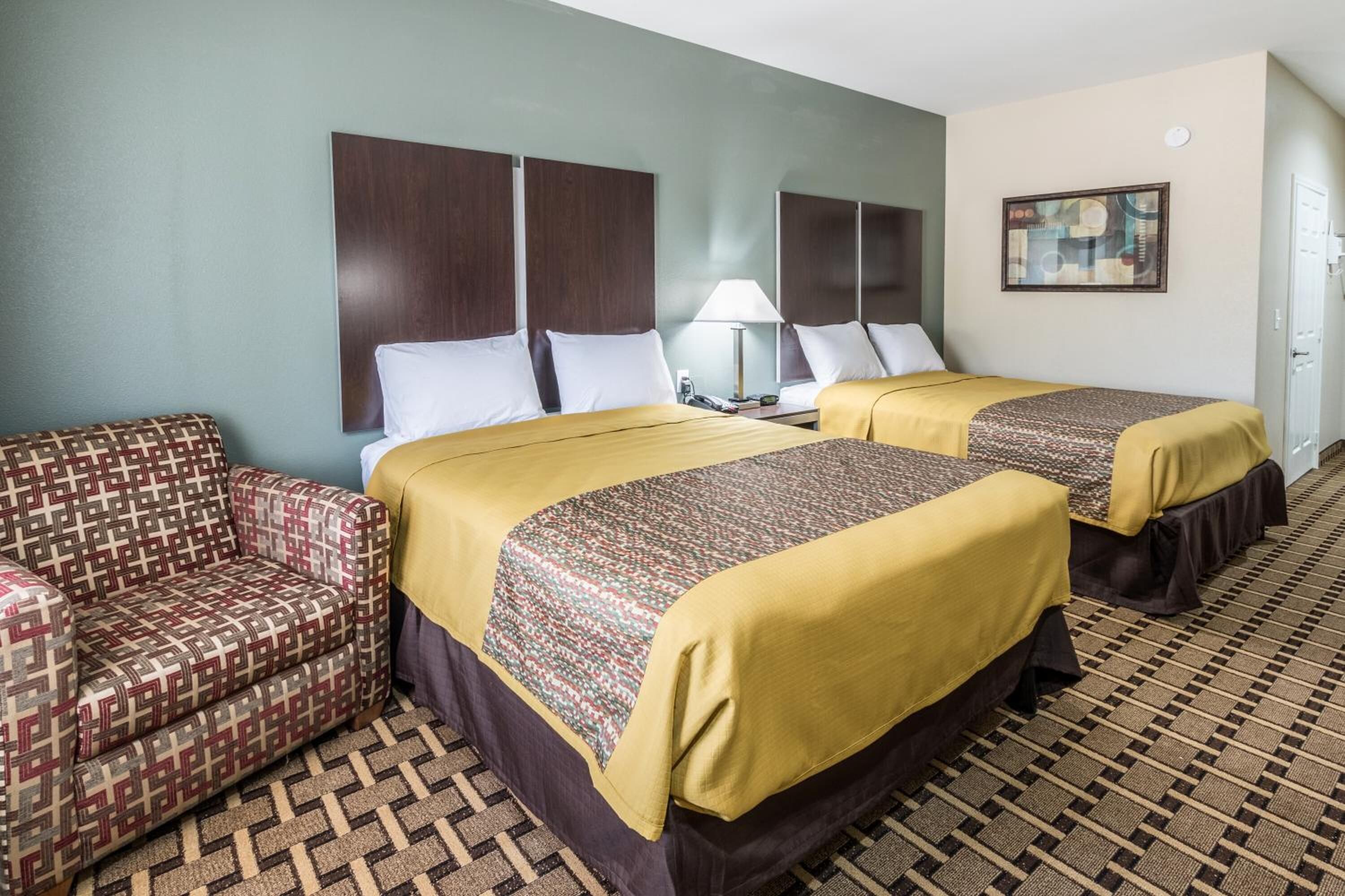 A hotel room with two beds, a sofa, and a patterned floor.