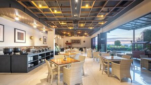 A spacious dining area with wicker furniture and a buffet setup. - Hotel NEO Eltari Kupang by Aston (Kupang)