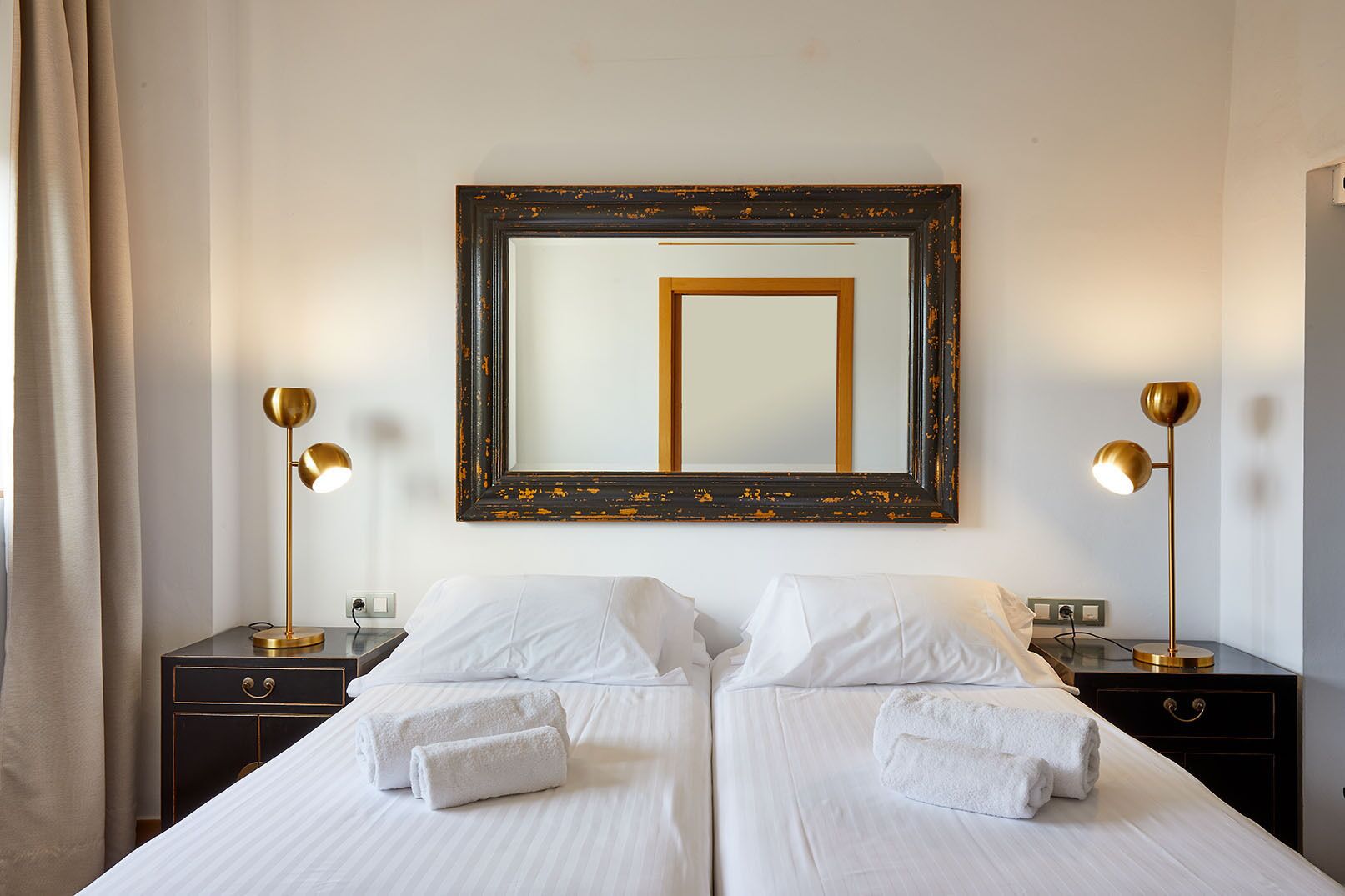 A hotel room with two beds, a large mirror, and two bedside lamps.