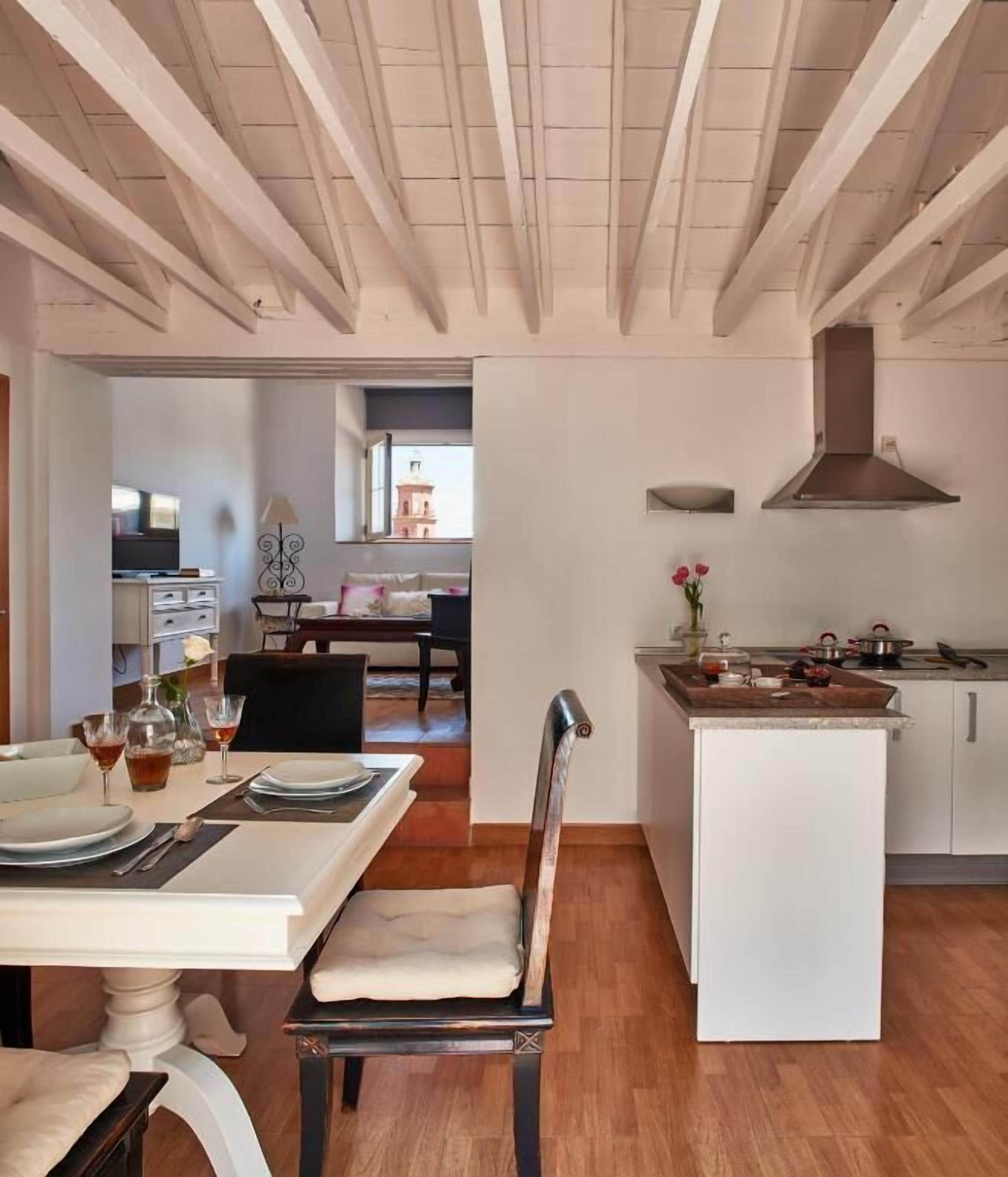 Una cocina amplia con una isla central, muebles blancos y una estufa moderna.