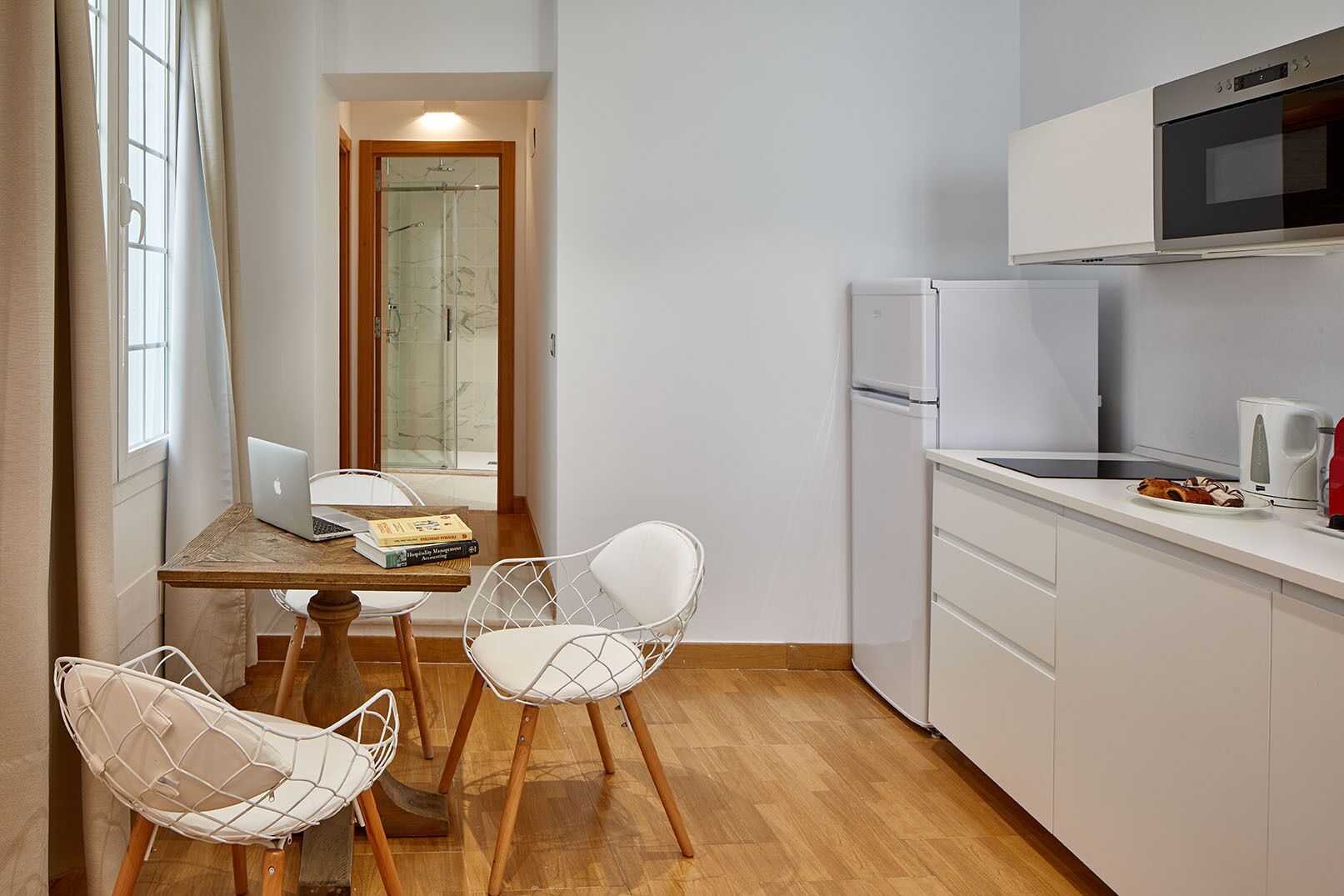A compact kitchen with a refrigerator, microwave, and a small dining area with two chairs and a table.