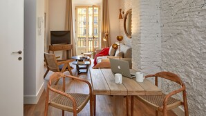 Una sala de estar acogedora con una mesa de madera, dos sillas de mimbre, un sofá, un televisor y un balcón con vistas.