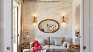 Una sala de estar moderna con una pared de ladrillo, un espejo redondo y dos lámparas de pie.