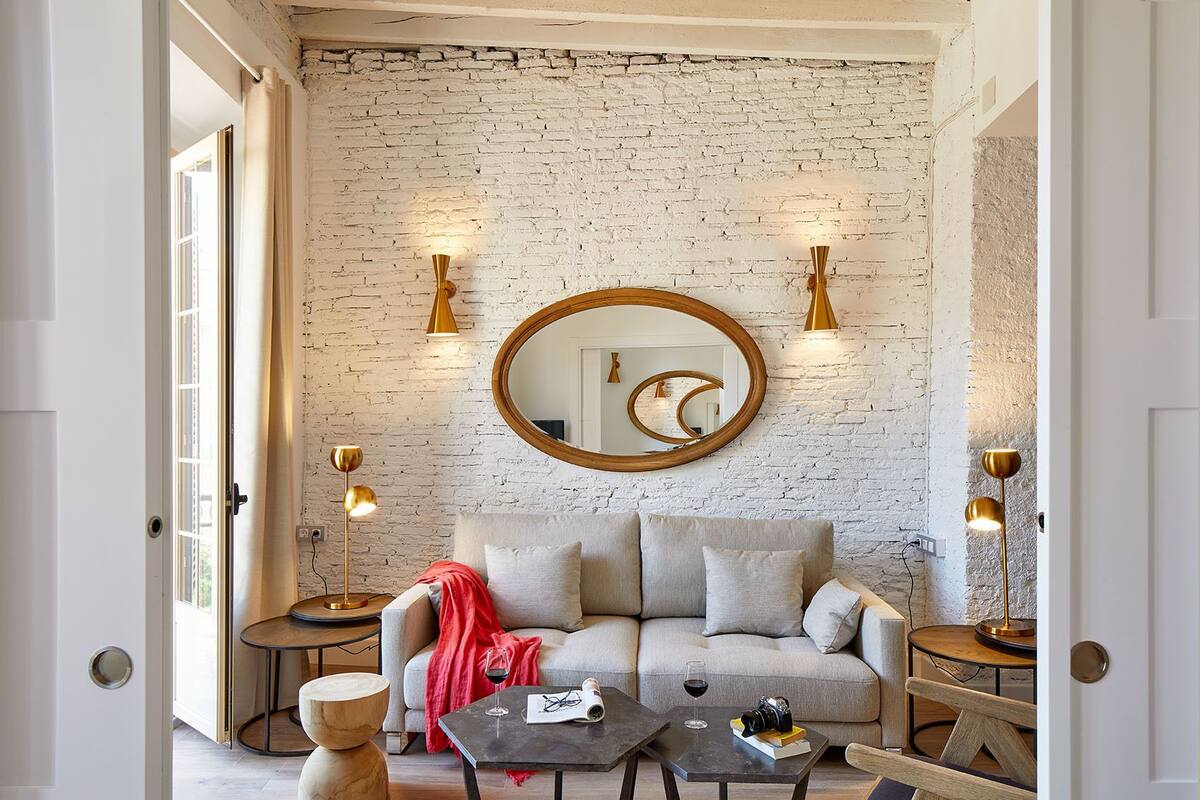 Una sala de estar moderna con una pared de ladrillo, un espejo redondo y dos lámparas de pie.