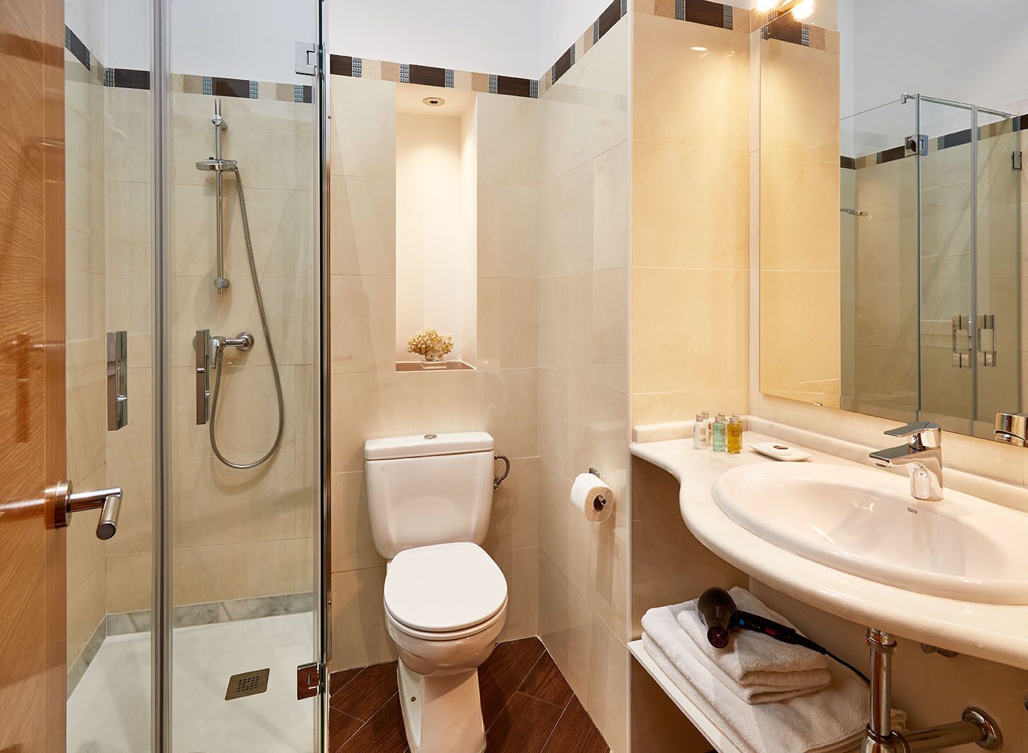 A modern bathroom with a glass-enclosed shower, a toilet, a sink with a mirror, and a towel rack.
