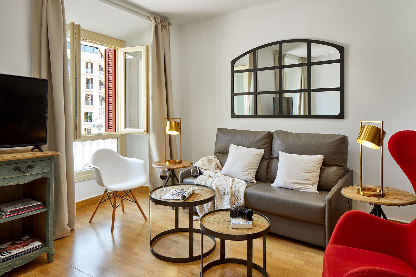 Una sala de estar con un sofá, dos sillones, un televisor y una mesa con bebidas.