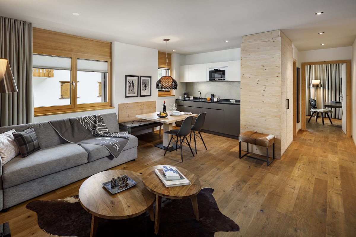 Ein modernes Wohnzimmer mit einem grauen Sofa, einem Holztisch und einem Essbereich mit Tisch und Stühlen.