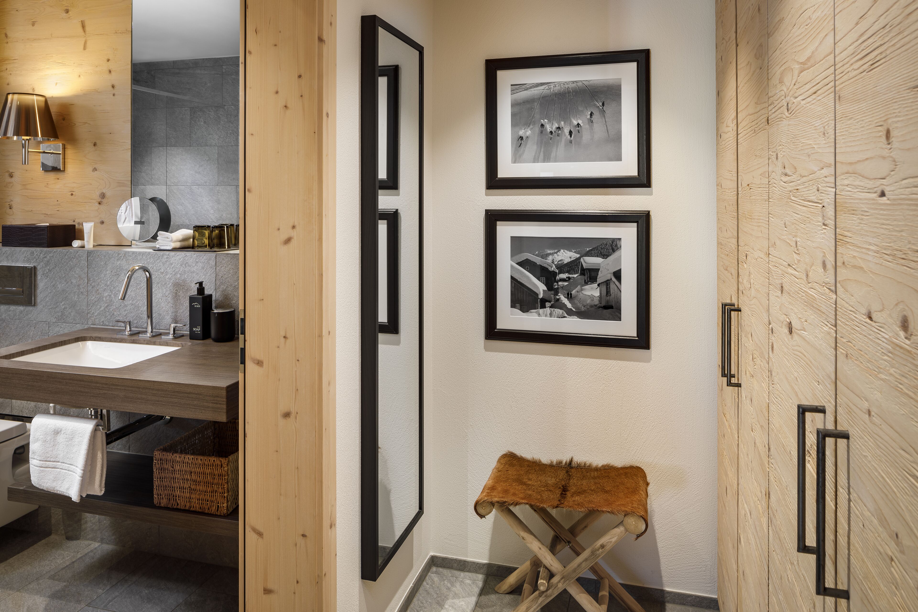 Ein modernes Badezimmer mit einem Holzbadezimmermöbel, einem großen Spiegel und zwei gerahmten Fotos an der Wand.