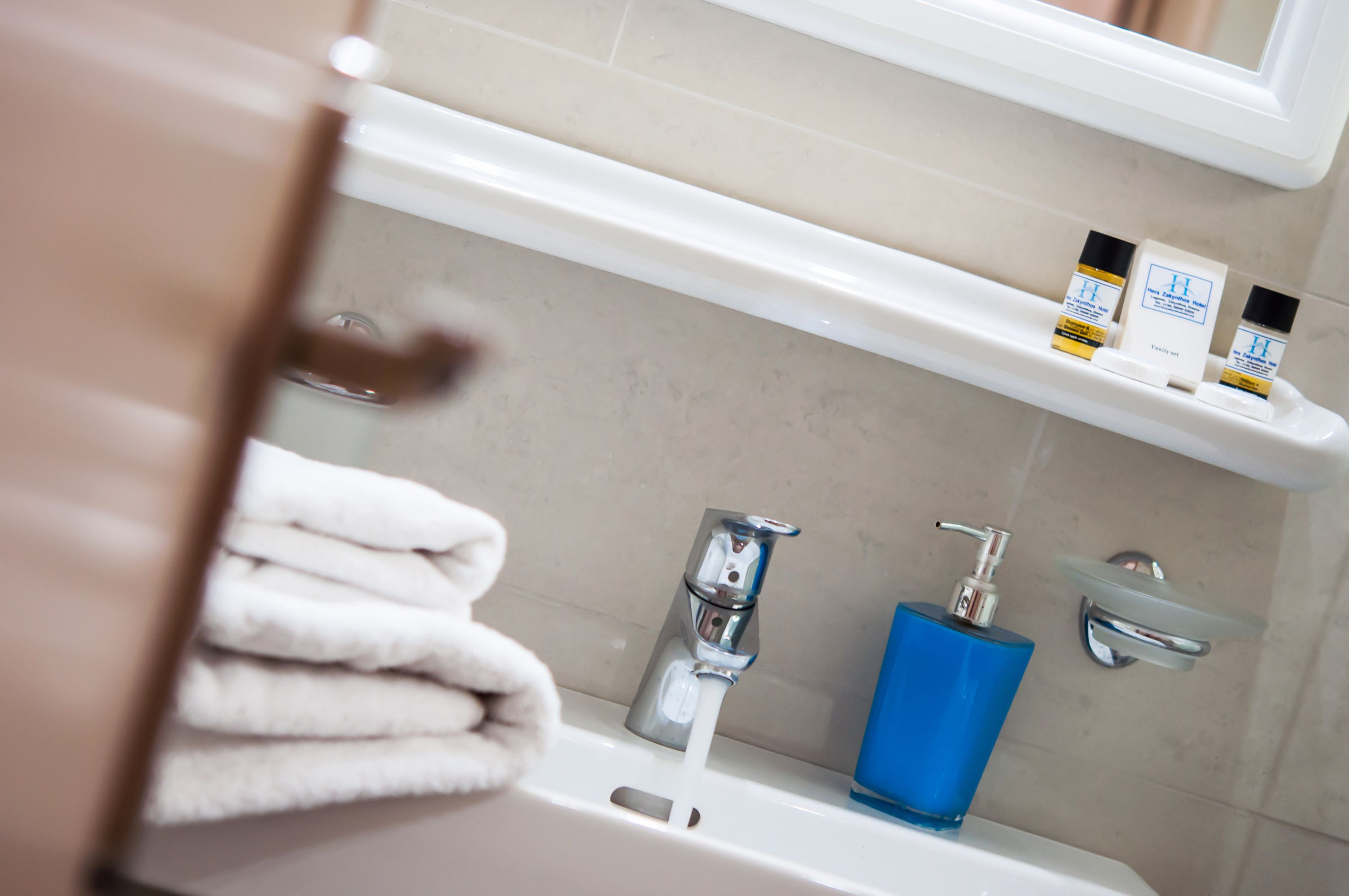 A bathroom with a sink, a mirror, and a shelf with toiletries.