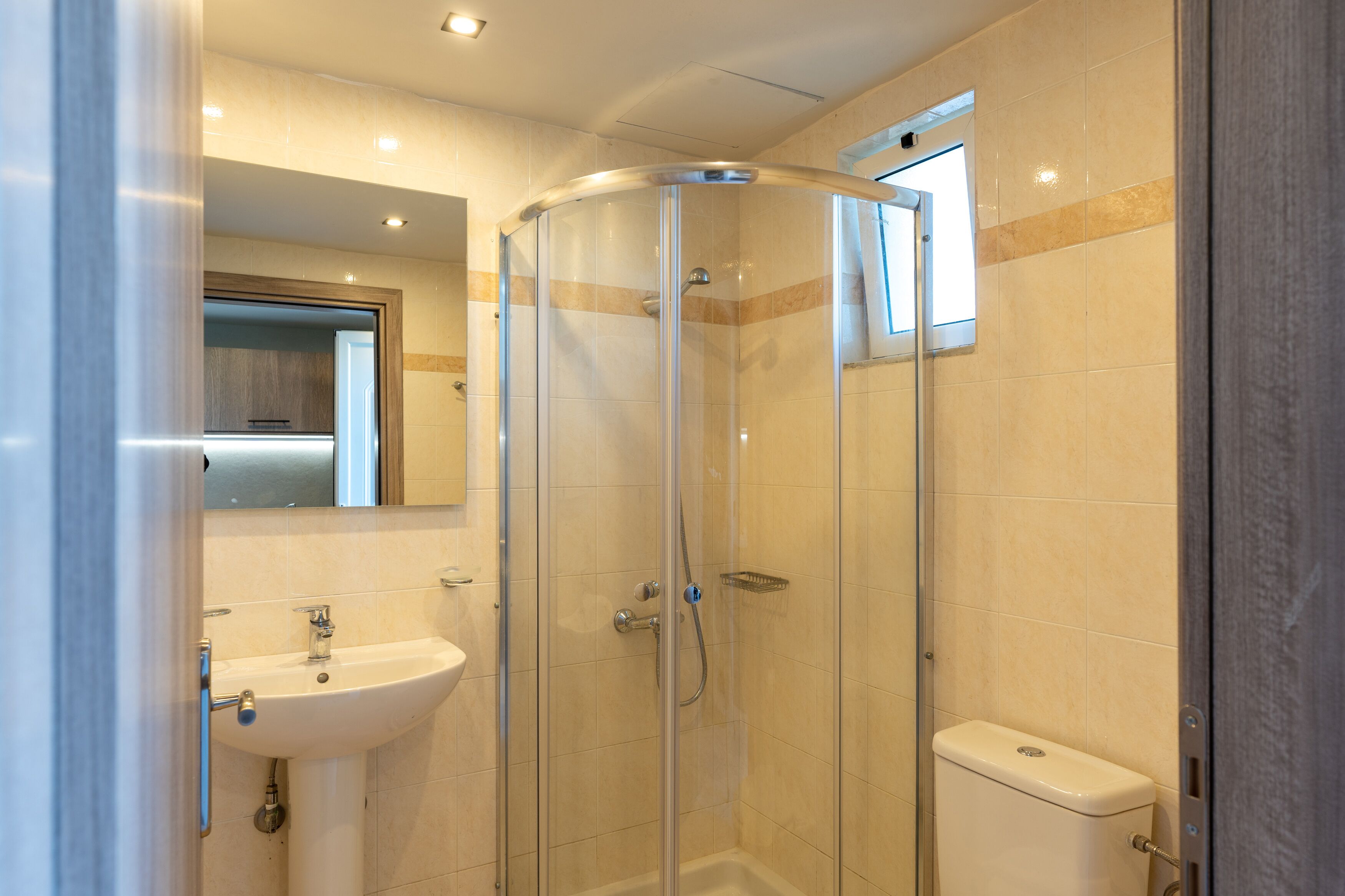Une salle de bain moderne avec une douche à parois de verre, un lavabo sur colonne et des toilettes.