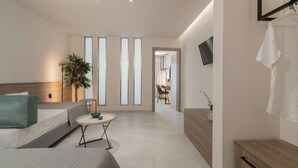 A modern hotel room with a bed, a small round table, a plant, and a TV mounted on the wall. - Hera Zakynthos Hotel (Zakynthos)