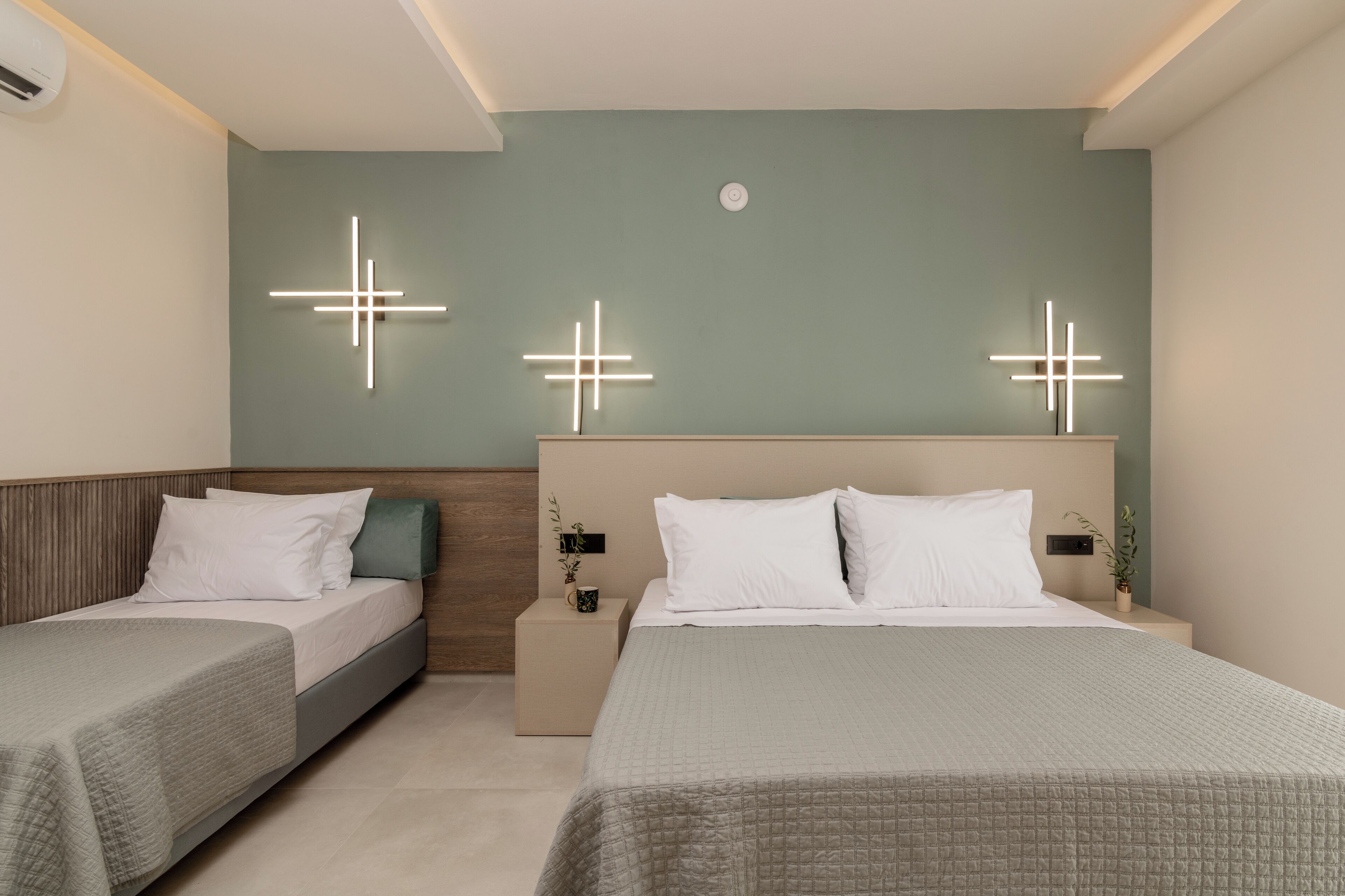 Et moderne hotelværelse med to senge, en neutral farveskala og dekorative væglamper.