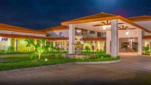 A hotel with a covered entrance, a fountain, and well-maintained gardens. - Hotel Coclé (Penonome)