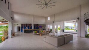 A spacious lobby with a reception desk, seating area, and a large window offering a view of the outside. - Hotel Coclé (Penonome)