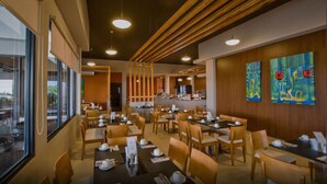 A modern restaurant with wooden paneling, multiple dining tables, and artwork on the walls. - Hotel Coclé (Penonome)