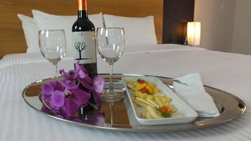 Un plateau avec une bouteille de vin, deux verres, des orchidées violettes et un plat de nourriture, le tout posé sur une table.