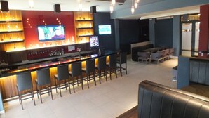 A bar area with a counter, multiple bar stools, and a television screen. - Hotel Coclé (Penonome)