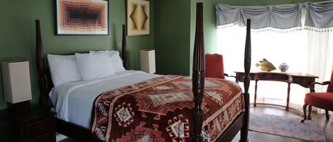 Un dormitorio con cama con dosel, una mesita de noche, un escritorio y una silla.