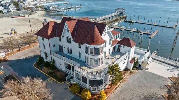 Een groot wit meerlaags huis met een rood dak, nabij een jachthaven met steigers en boten.