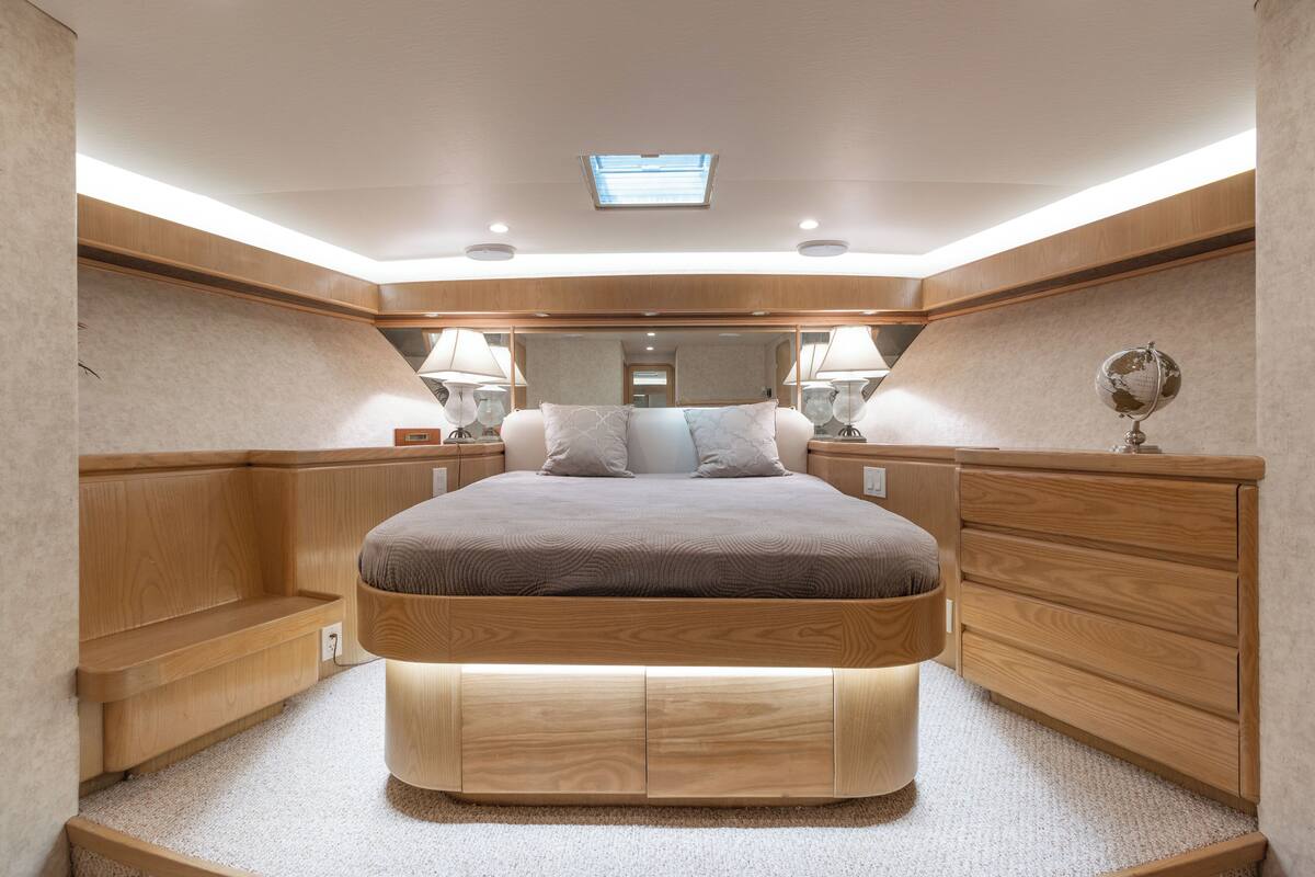 Een moderne slaapkamer met een centraal geplaatst bed, een houten hoofdeinde, nachtkastjes en een dakraam.