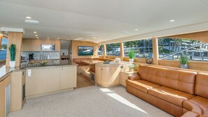 Een moderne keuken met een centraal eiland, een zithoek met een bank en grote ramen met uitzicht op de jachthaven.