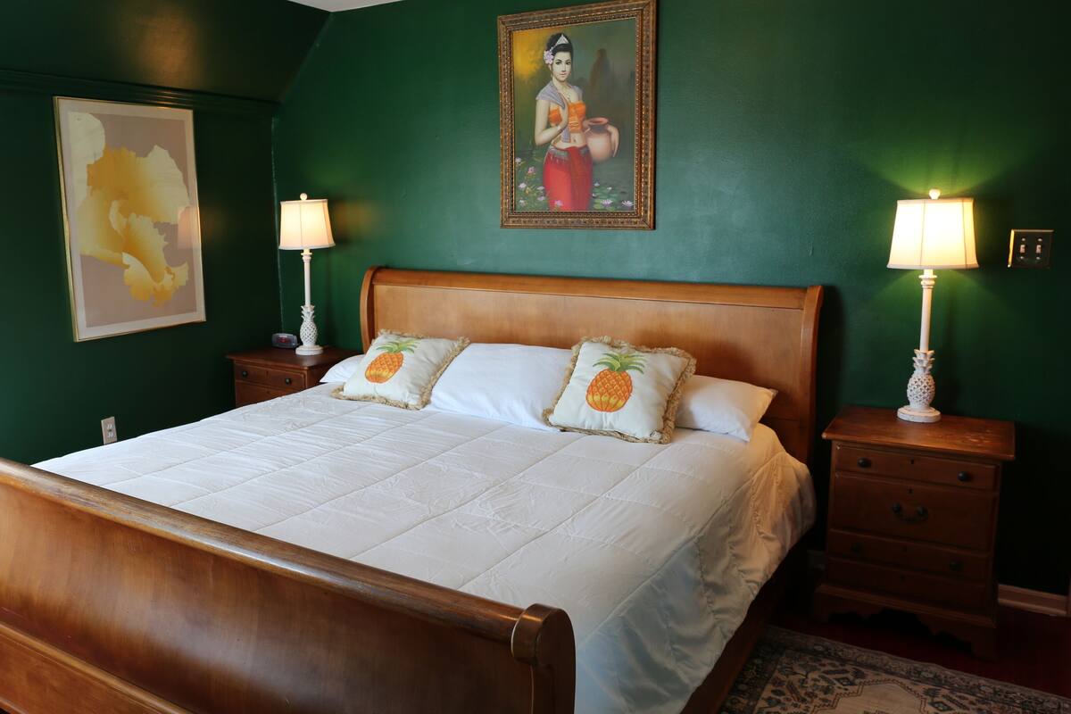 Een slaapkamer met een houten bed, twee nachtkastjes, een schilderij en twee wandlampen.
