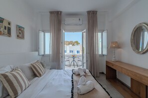 A hotel room with a bed, a bedside table, a mirror, and a view of the outside. - Eucalyptus Houses (Santorini)