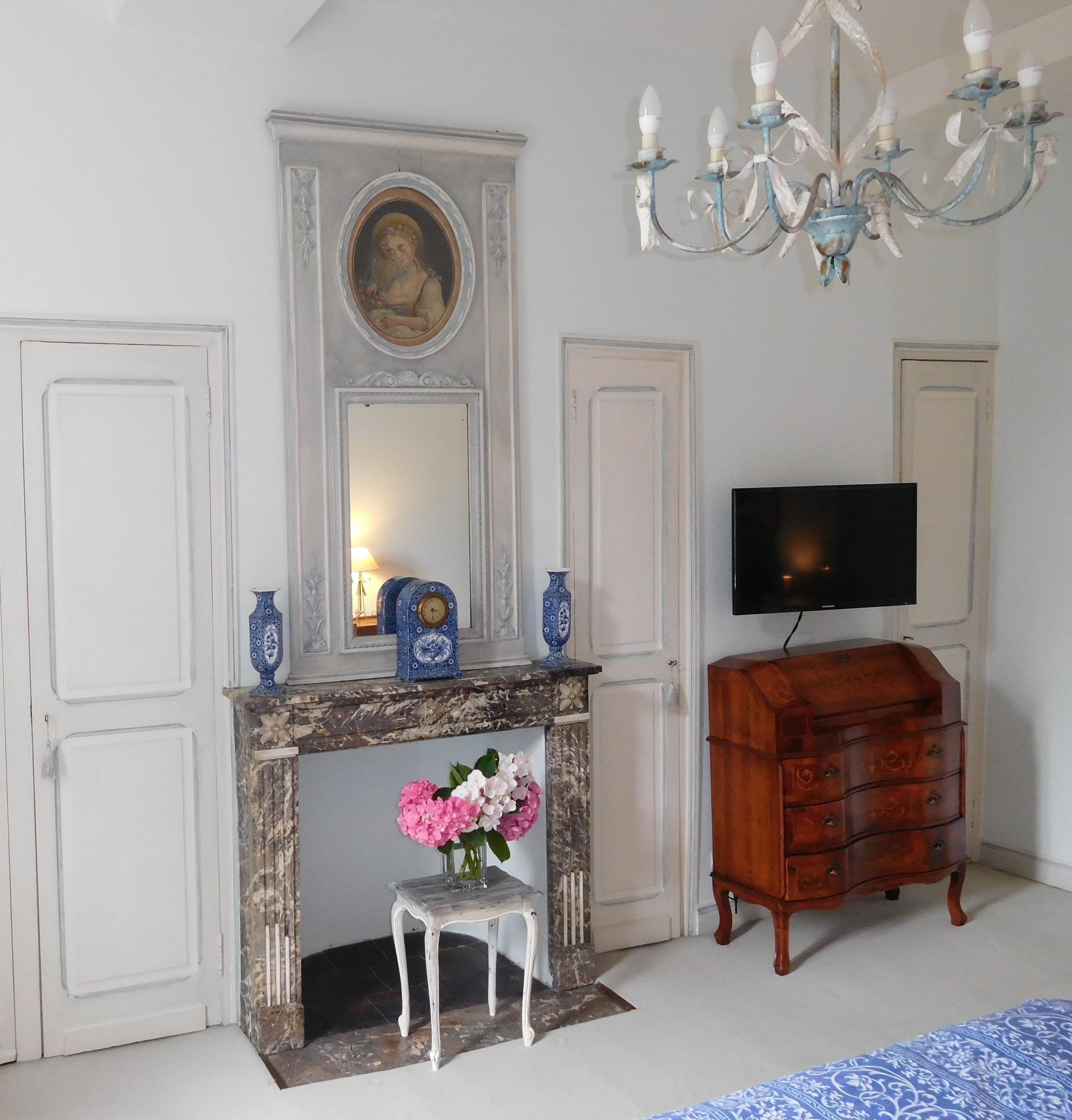A room with a fireplace, a television, and a wooden dresser.