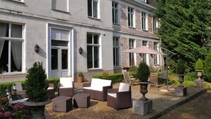 A building with a brick facade, multiple windows, and outdoor seating with a table and chairs. - Chambres d'Hôtes Château de Courcelette (Lannoy)