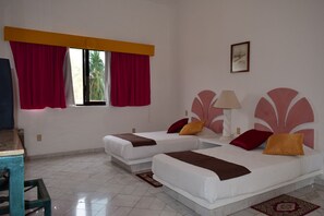 A hotel room with two beds, a desk, and a window with curtains.