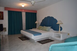 A bedroom with a bed, two bedside tables, a ceiling fan, and a television.